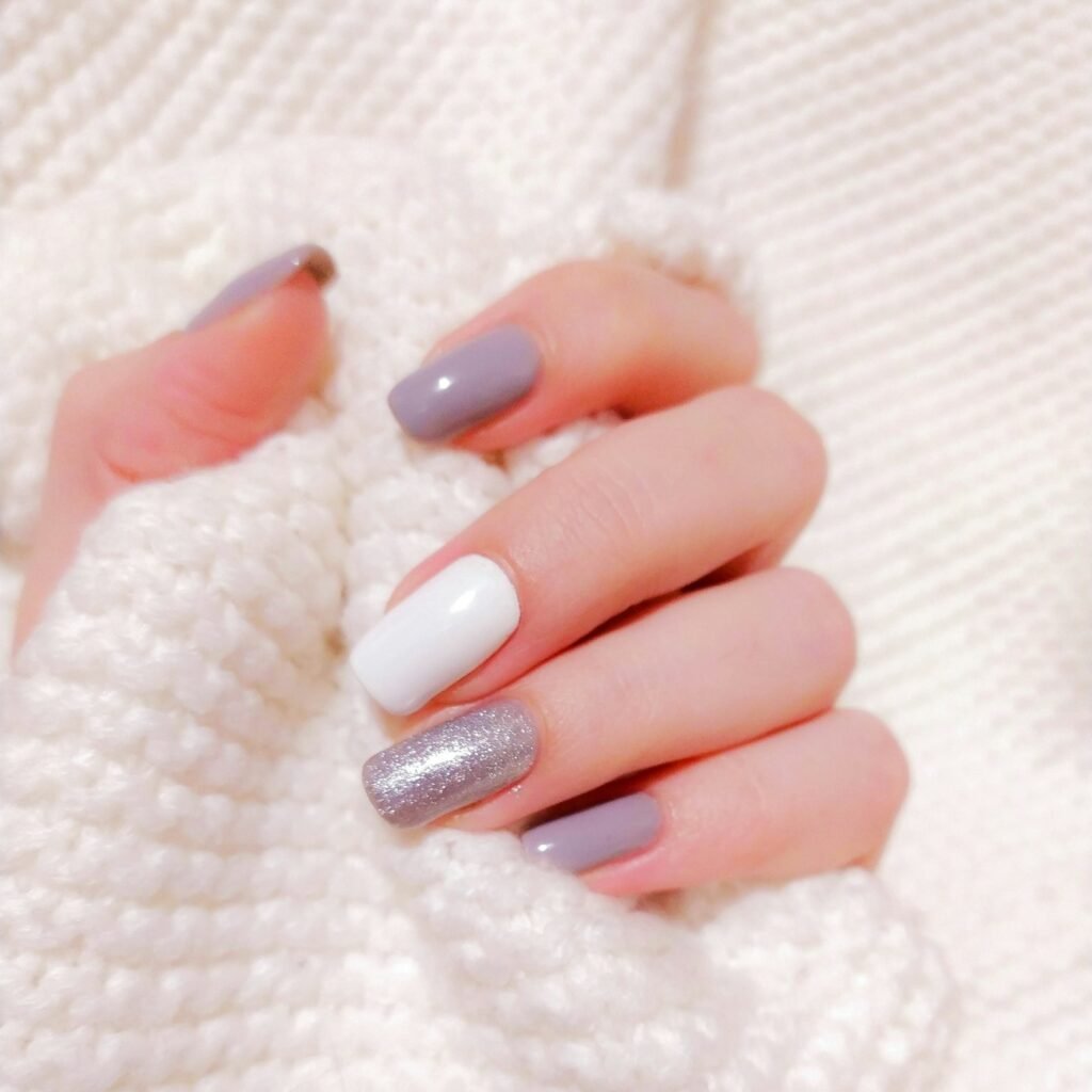 Hand met lila, witte en glitternagels