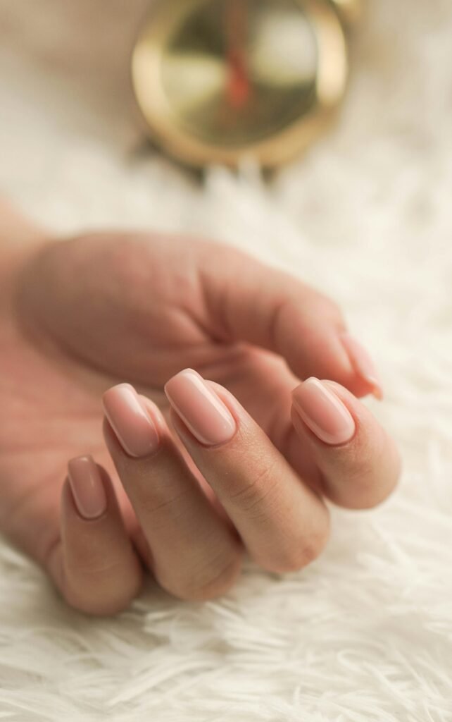 Hand met zachtroze gemanicuurde nagels